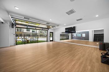 A room with a wooden floor and a large window with a view of a parking lot.